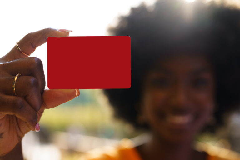 Portrait of young american woman with afro hairstyle holding red plastic credit card